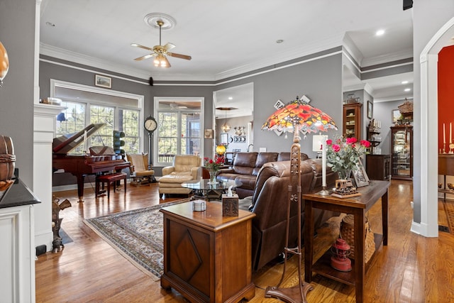 living room with ornamental molding, a ceiling fan, and wood finished floors