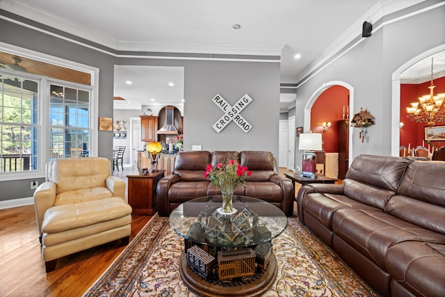 living room featuring arched walkways, dark wood-style flooring, crown molding, a notable chandelier, and baseboards