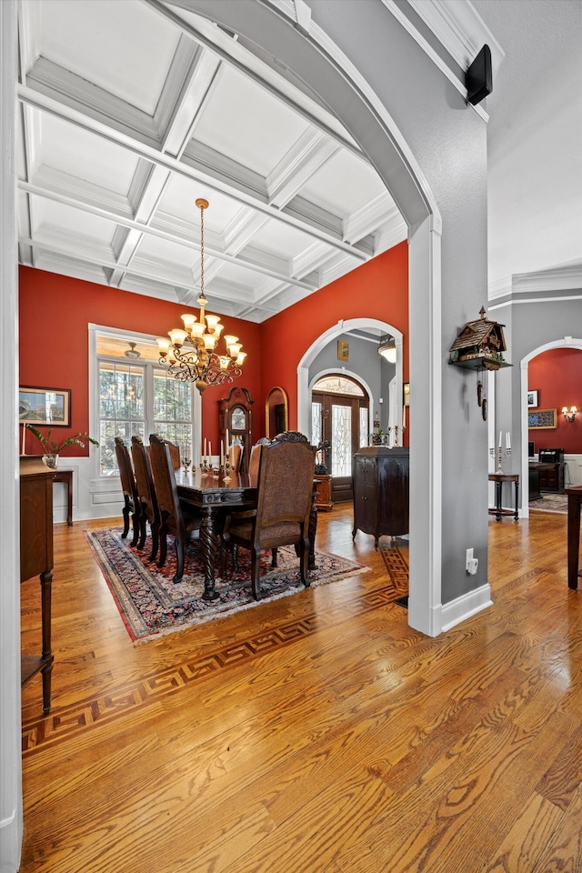 dining space with light wood-style flooring, arched walkways, and a wealth of natural light