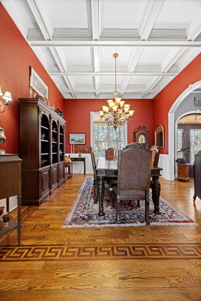 dining room with arched walkways, beam ceiling, light wood-style flooring, and a notable chandelier