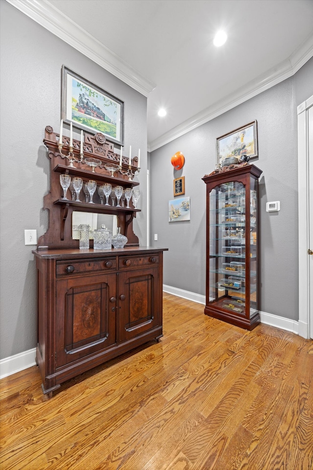 bar featuring ornamental molding, baseboards, and light wood finished floors