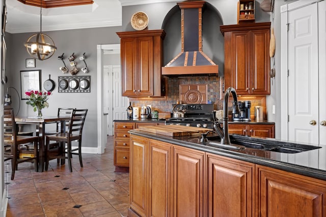 kitchen with wall chimney range hood, stove, a sink, and ornamental molding