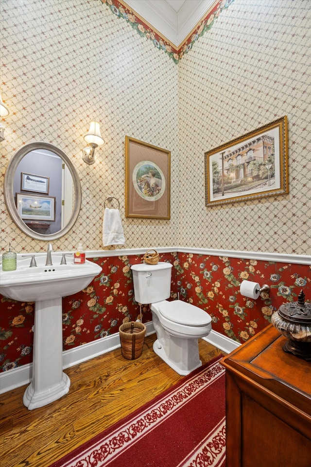 bathroom featuring wood finished floors, baseboards, toilet, and wallpapered walls