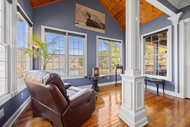 living area featuring lofted ceiling, decorative columns, baseboards, and wood finished floors