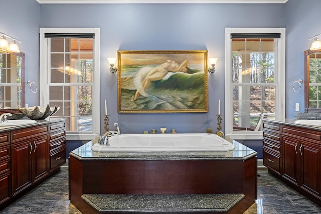 bathroom featuring two vanities, a garden tub, and a sink