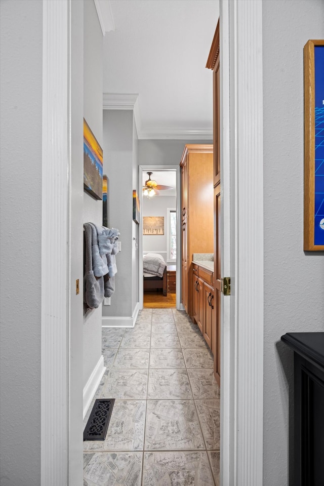 ensuite bathroom featuring visible vents, ornamental molding, ceiling fan, ensuite bath, and baseboards