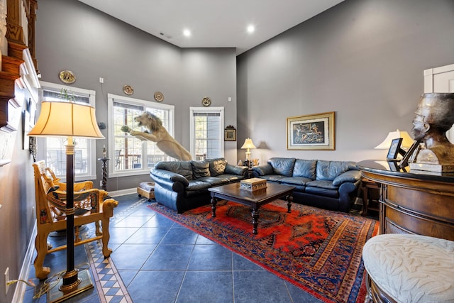 living area featuring recessed lighting, dark tile patterned flooring, a high ceiling, visible vents, and baseboards