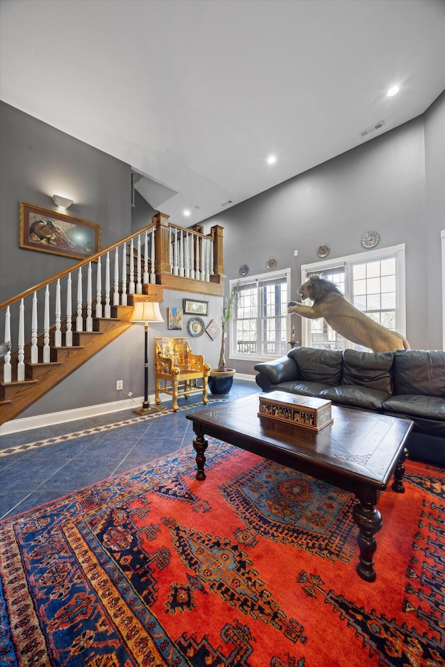 tiled living area with baseboards, visible vents, stairway, a high ceiling, and recessed lighting