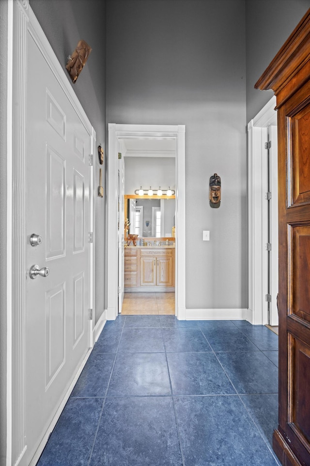 foyer featuring baseboards and dark tile patterned flooring