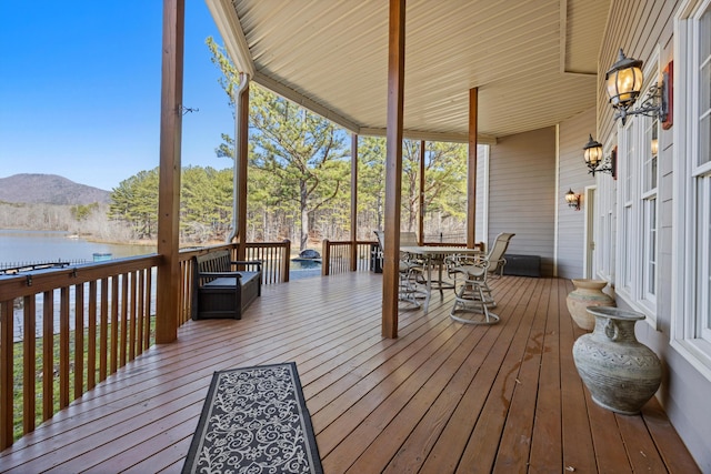 wooden deck with outdoor dining area and a water and mountain view