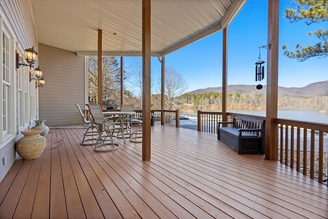 wooden terrace featuring outdoor dining space and a water and mountain view