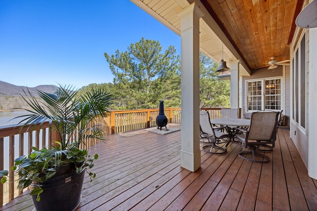 wooden deck featuring outdoor dining space and a ceiling fan