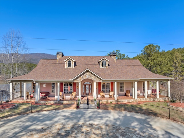 view of front of home featuring a fenced front yard, a chimney, a porch, a shingled roof, and a gate