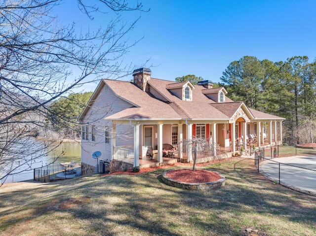 view of front of property featuring covered porch, a shingled roof, a chimney, and a front yard