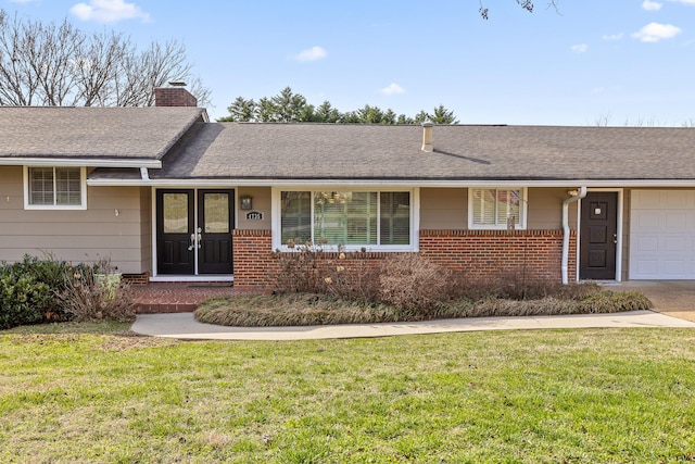 ranch-style home featuring brick siding, a chimney, an attached garage, and a front lawn