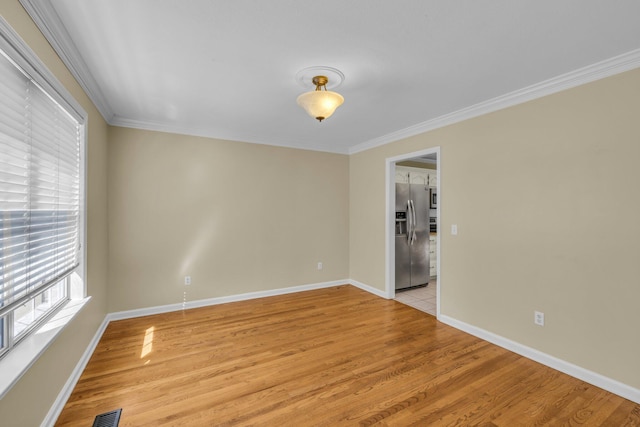 empty room featuring ornamental molding and light wood-type flooring