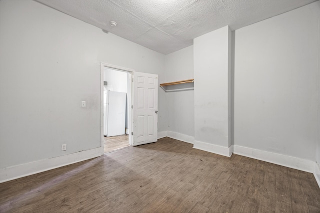 unfurnished bedroom with white refrigerator, dark hardwood / wood-style flooring, and a textured ceiling