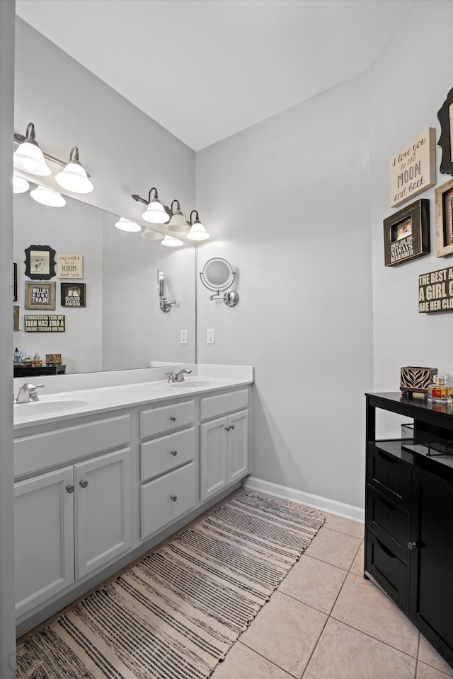 bathroom with double vanity, baseboards, a sink, and tile patterned floors