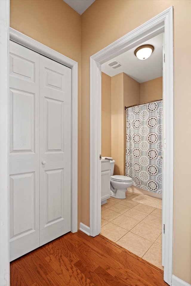 bathroom with toilet, a closet, wood finished floors, and visible vents