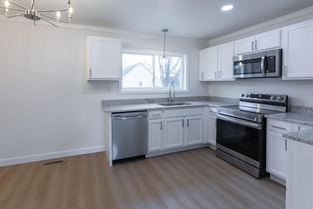 kitchen with appliances with stainless steel finishes, a chandelier, sink, and white cabinets