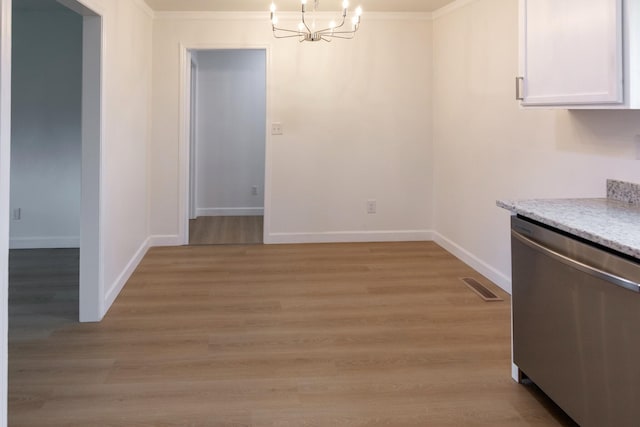 unfurnished dining area with crown molding, a notable chandelier, and light wood-type flooring