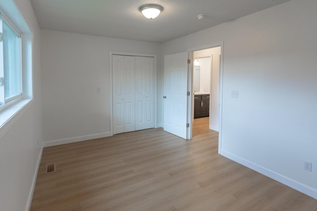 unfurnished bedroom with a closet, light hardwood / wood-style flooring, and a textured ceiling