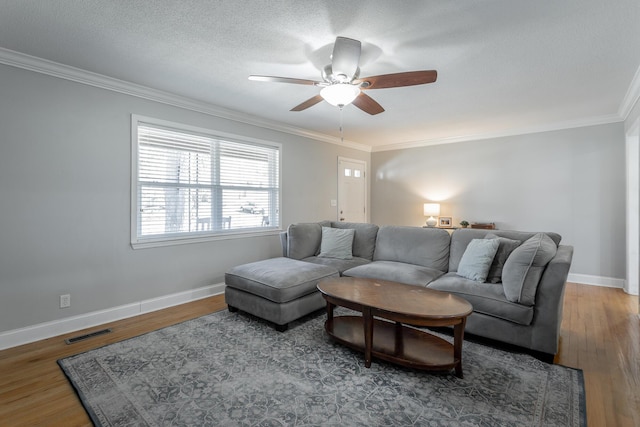 living area with visible vents, ornamental molding, a textured ceiling, wood finished floors, and baseboards