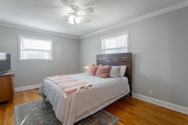 bedroom with multiple windows, crown molding, light wood-style flooring, and baseboards