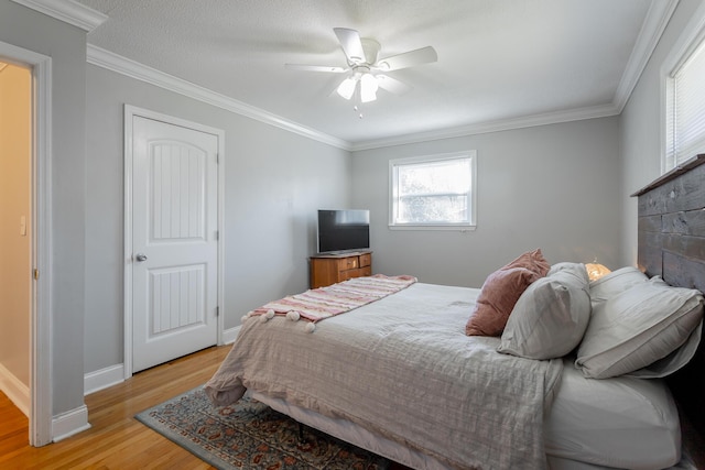 bedroom featuring a ceiling fan, light wood-style floors, baseboards, and ornamental molding