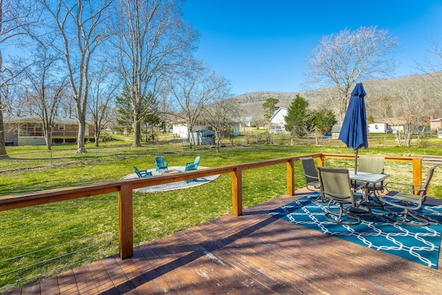 wooden deck with a lawn, a mountain view, outdoor dining area, and fence