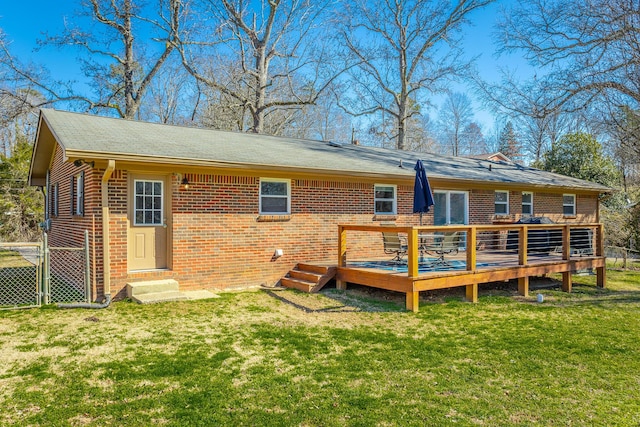 back of house featuring brick siding, a lawn, and entry steps