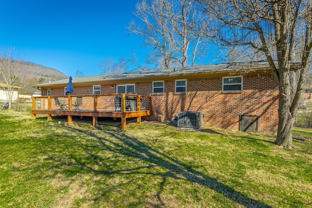 back of house featuring brick siding, a deck with mountain view, central AC, and a yard