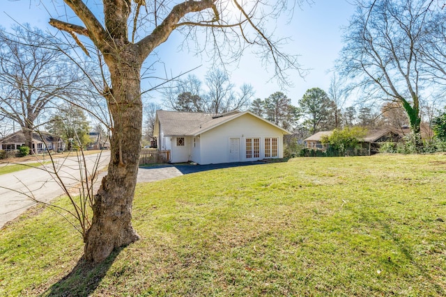 exterior space featuring french doors, fence, and a front lawn