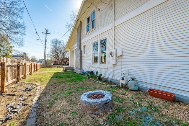 view of side of property featuring an outdoor fire pit and a fenced backyard