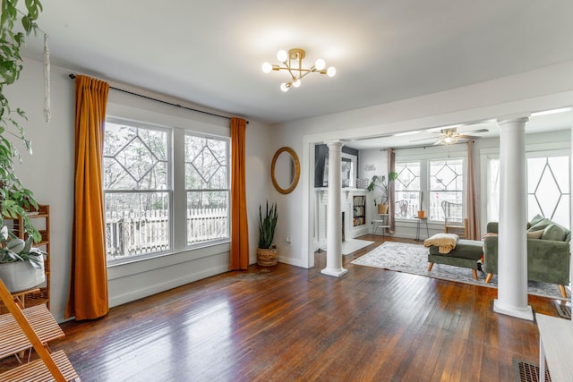 interior space with dark wood finished floors, a fireplace, and decorative columns