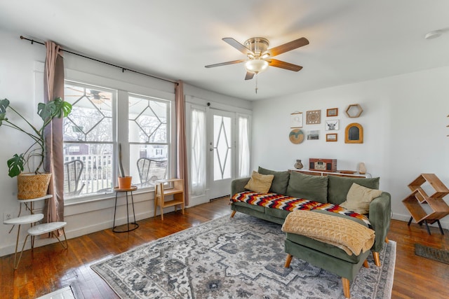 living area featuring ceiling fan, baseboards, and dark wood-type flooring