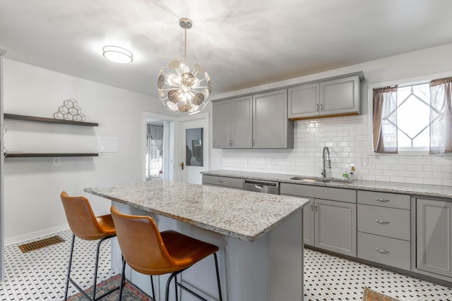 kitchen featuring decorative light fixtures, a center island, gray cabinetry, open shelves, and a sink