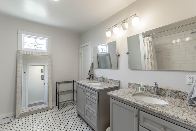 full bath with two vanities, a sink, and a wealth of natural light