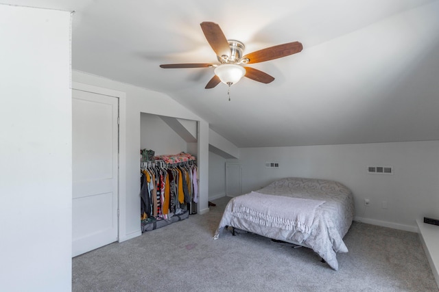 carpeted bedroom featuring lofted ceiling, a closet, visible vents, and ceiling fan