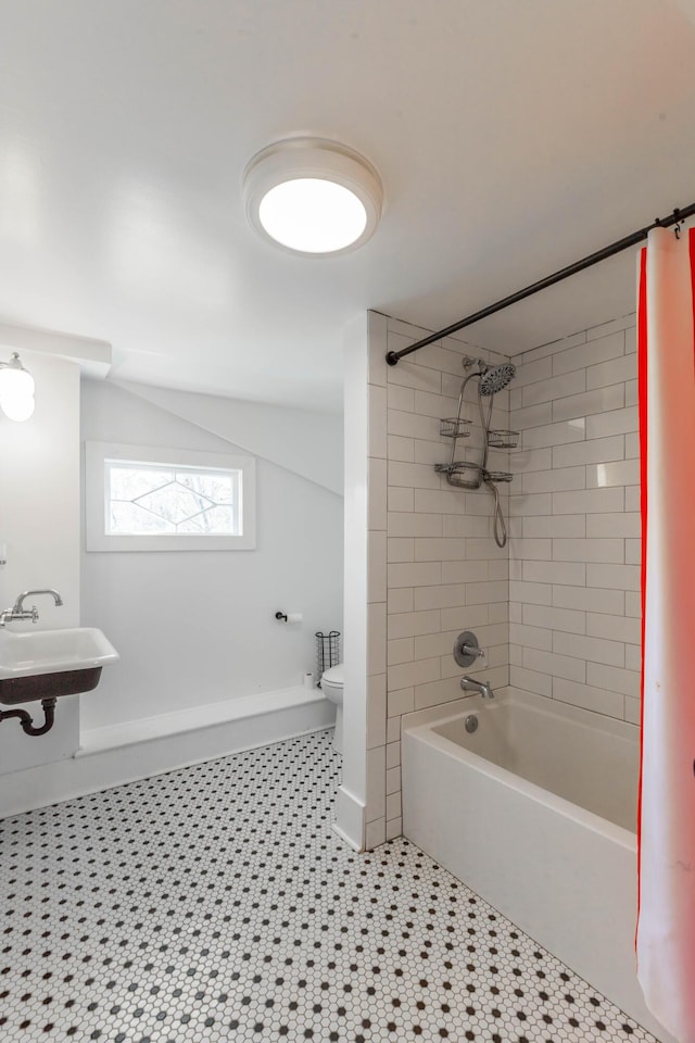 bathroom with lofted ceiling, toilet, shower / tub combo, a sink, and baseboards