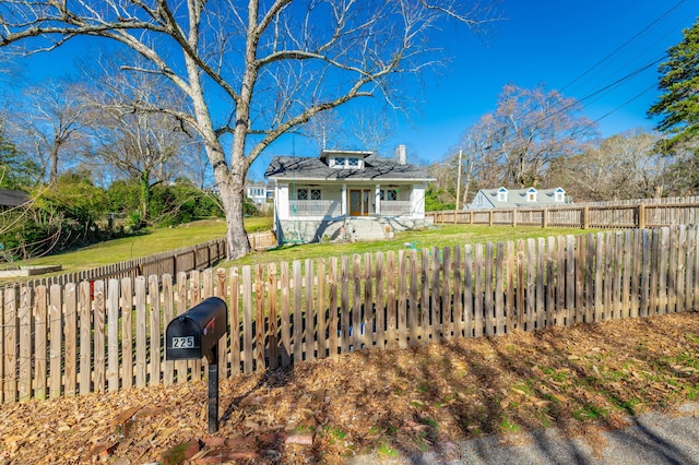 view of front facade featuring a fenced backyard, a chimney, and a front lawn