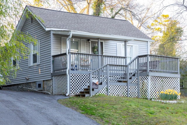 view of front of home featuring covered porch, a front lawn, and roof with shingles