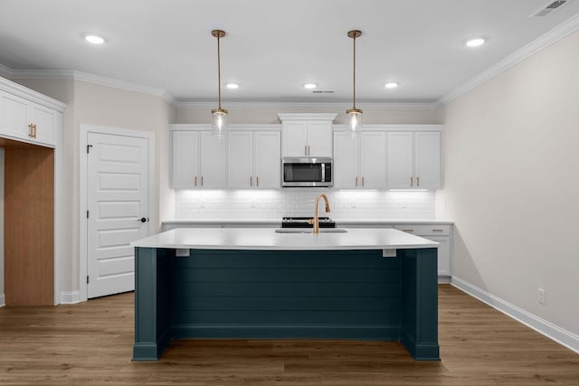 8918 Knolling Lp Unit 32, Ooltewah, TN 37363 - kitchen with stainless steel microwave, a sink, white cabinetry, a center island with sink, and tasteful backsplash