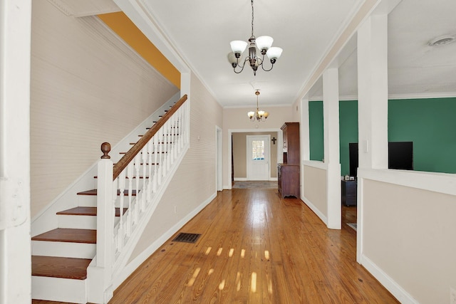 foyer entrance featuring an inviting chandelier, wood-type flooring, and ornamental molding