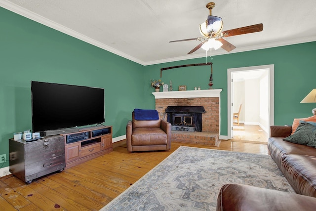 living room featuring ceiling fan, ornamental molding, a brick fireplace, and light hardwood / wood-style flooring