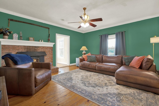 living room featuring ceiling fan, ornamental molding, a fireplace, and hardwood / wood-style floors