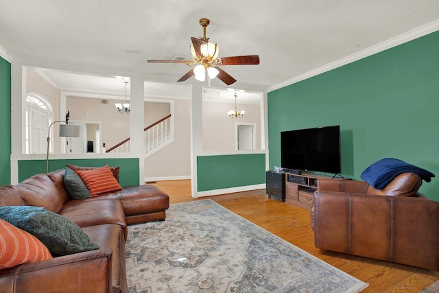 living room with hardwood / wood-style flooring, ornamental molding, and ceiling fan with notable chandelier