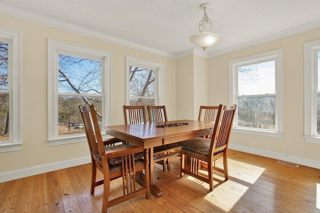 dining space with ornamental molding, light hardwood / wood-style flooring, and a wealth of natural light