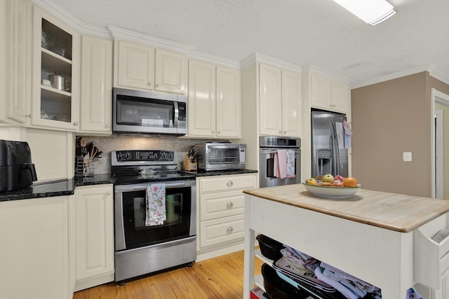 kitchen featuring appliances with stainless steel finishes, white cabinets, backsplash, a textured ceiling, and light hardwood / wood-style flooring