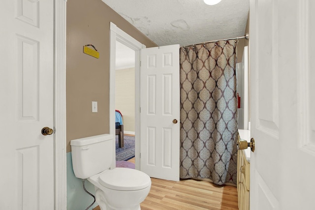 bathroom featuring hardwood / wood-style floors, a textured ceiling, and toilet